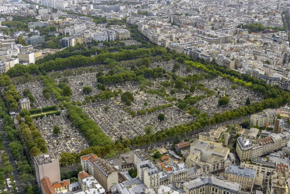 Aerial view of Père Lachaise Cemetery in Paris — tree-lined blocks filled with graves, surrounded by dense urban buildings